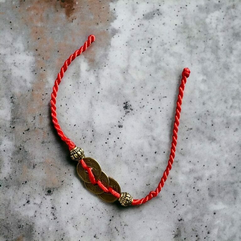 Ein rotes Armband mit einem goldenen Anhänger.